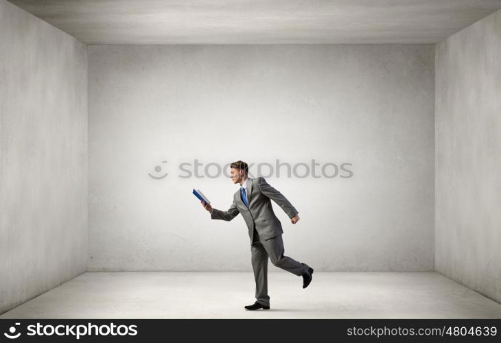 Man reading on the run. Young businessman running with opened book in hand