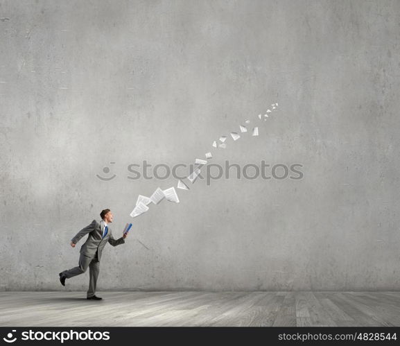 Man reading on the run. Young businessman running with opened book in hand