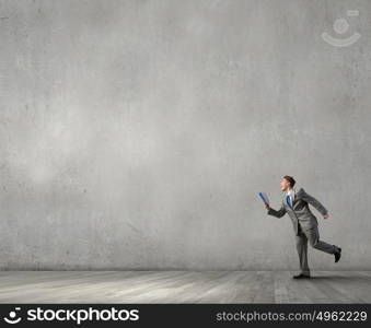 Man reading on the run. Young businessman running with opened book in hand