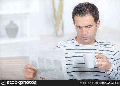 Man reading paper holding cup