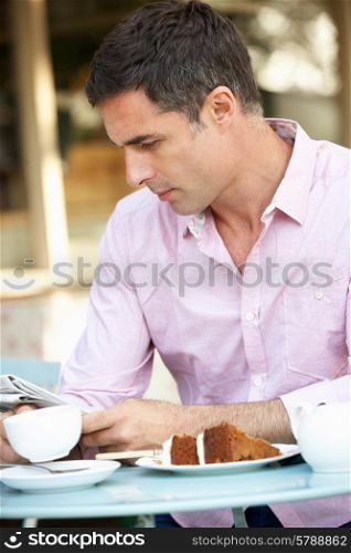 Man reading paper outside cafe