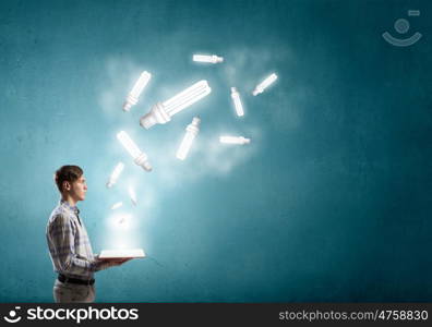 Man reading red book. Young student guy with opened book in hands and glass light bulb