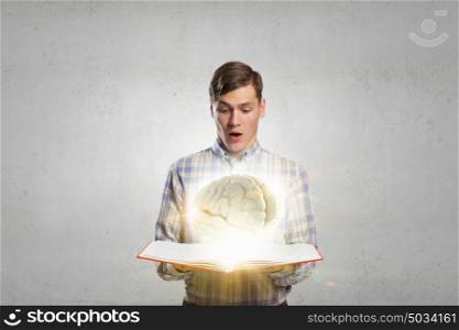 Man reading red book. Young student guy with opened book in hands