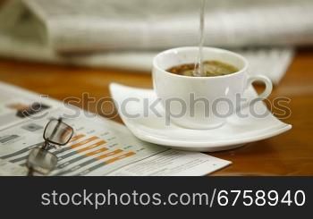 Man reading the newspaper and reaching for his morning coffee.