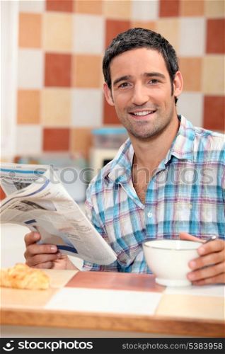 Man reading the newspaper while having breakfast
