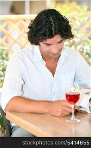 Man reading with a glass of rose in the sunshine
