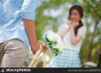 Man ready to give flowers to girlfriend in the park