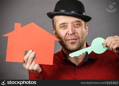 Man, real estate agent holding red house model with keys. Being new home ownership concept.. Man holding red house model and home keys