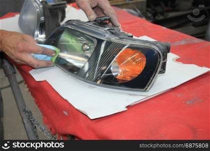 Man refurbishing a car headlight with clear coating