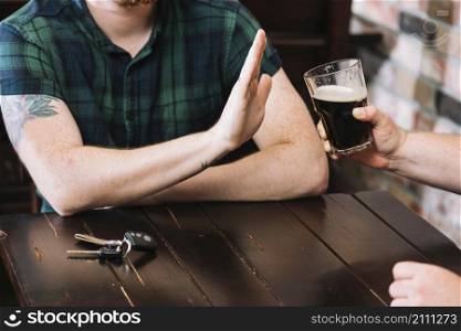 man refusing glass rum offered by his friend