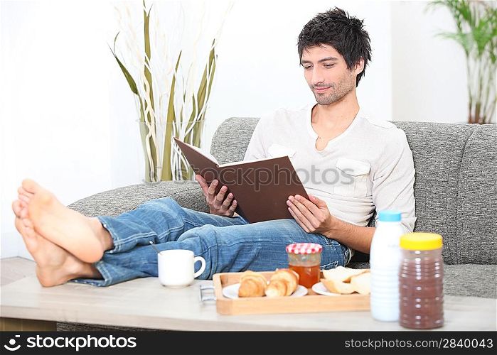 man relaxed in sofa with album at breakfast time