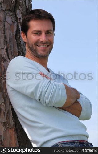 man relaxing against a tree
