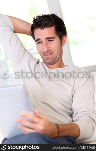 Man relaxing at home with electronic tablet