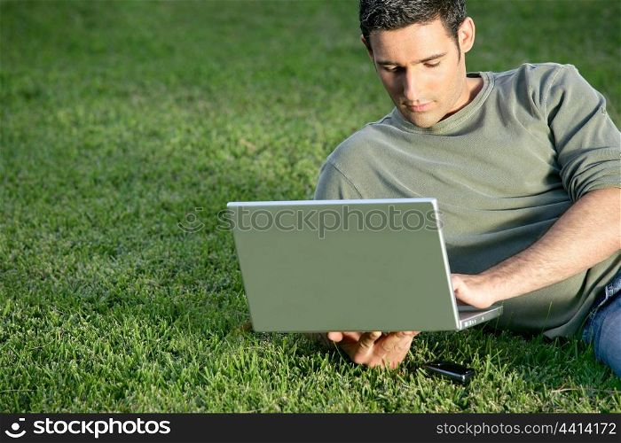 Man relaxing in field with laptop