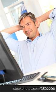 Man relaxing in office with stretched arms