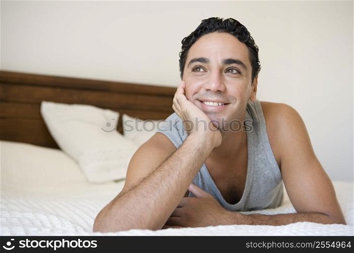 Man relaxing on bed in bedroom smiling (selective focus)