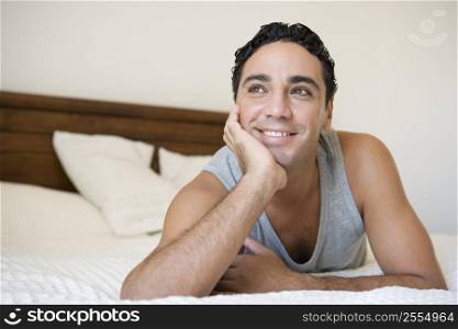 Man relaxing on bed in bedroom smiling (selective focus)