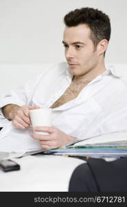 man relaxing on bed with hot drink in mug