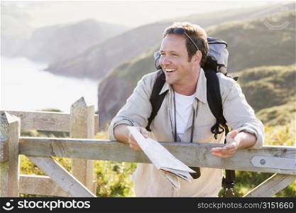 Man relaxing on cliffside path holding map and laughing