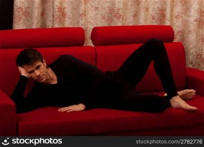 Man relaxing on red sofa
