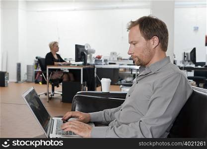 Man relaxing on sofa with laptop