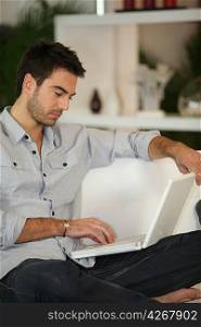 Man relaxing on sofa with laptop