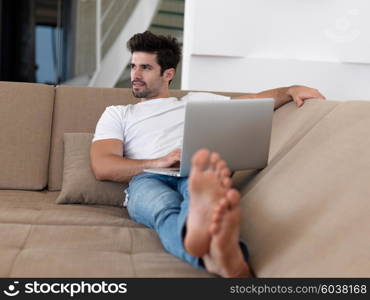 Man Relaxing On Sofa With Laptop In New Home