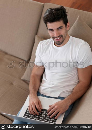 Man Relaxing On Sofa With Laptop In New Home