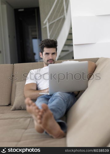 Man Relaxing On Sofa With Laptop In New Home