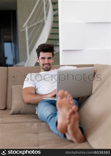 Man Relaxing On Sofa With Laptop In New Home