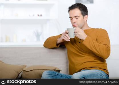 man relaxing on the couch and having a tea
