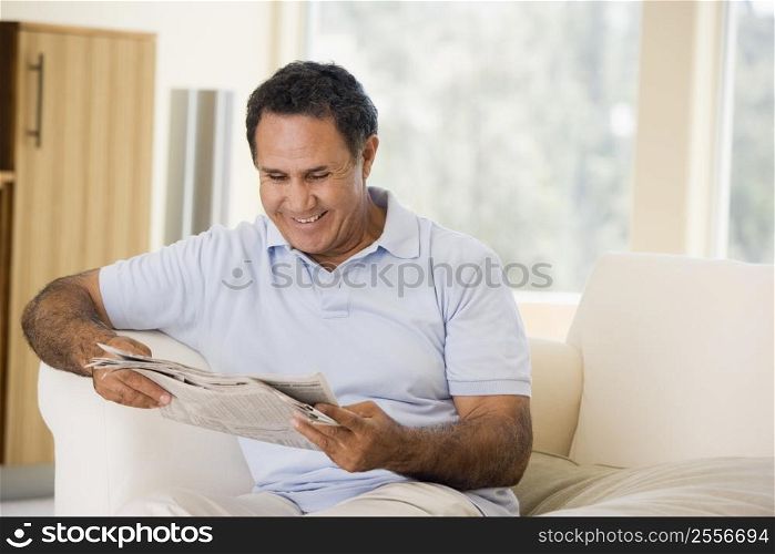 Man relaxing with newspaper in living room and smiling