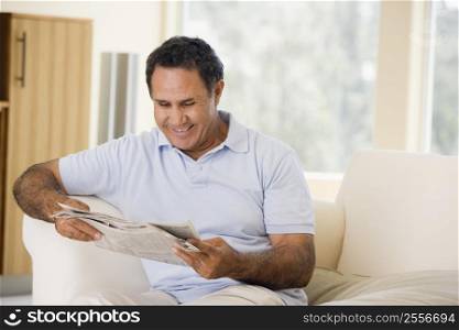 Man relaxing with newspaper in living room and smiling