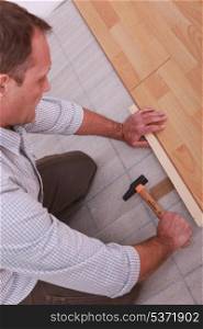 Man renovating the floor with a hammer