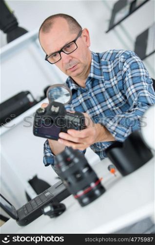 man repairing a camera at his workplace