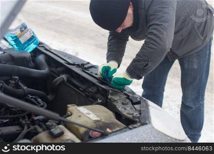 man repairing a car in winter