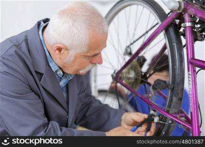 man repairing bike gear in his workshop
