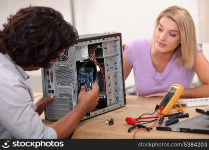 man repairing computer under his wife&rsquo;s