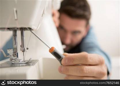 man repairing sewing machine with a screwdriver