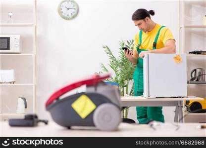 Man repairman repairing vacuum cleaner and fridge 