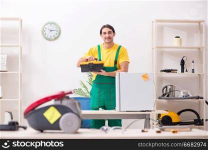 Man repairman repairing vacuum cleaner and fridge 