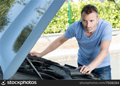 man repairs under the hood of the car