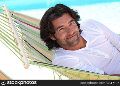 Man resting in hammock next to swimming pool
