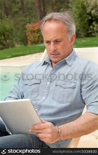 Man resting in long chair with touchpad
