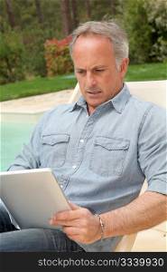 Man resting in long chair with touchpad