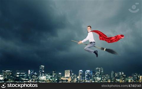 Man ride broom. Young businessman flying on broom high in sky