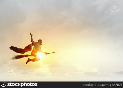 Man ride broom. Young businessman flying on broom high in sky