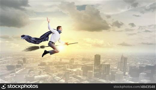 Man ride broom. Young businessman flying on broom high in sky