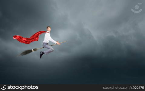 Man ride broom. Young businessman flying on broom high in sky