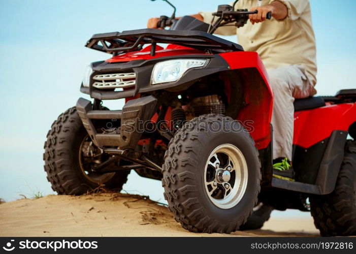 Man rides on atv, downhill riding in desert sands, action view. Male person on quad bike, sandy race, dune safari in hot sunny day, 4x4 extreme adventure, quad-biking. Man in helmet rides on atv in desert, action view